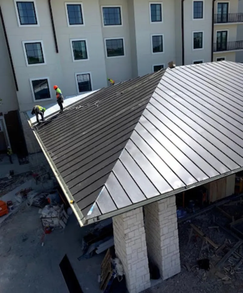 Crew installing standing seam metal roof panels on a commercial project in Upper Southampton